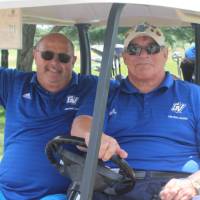 2 men in blue in golf cart